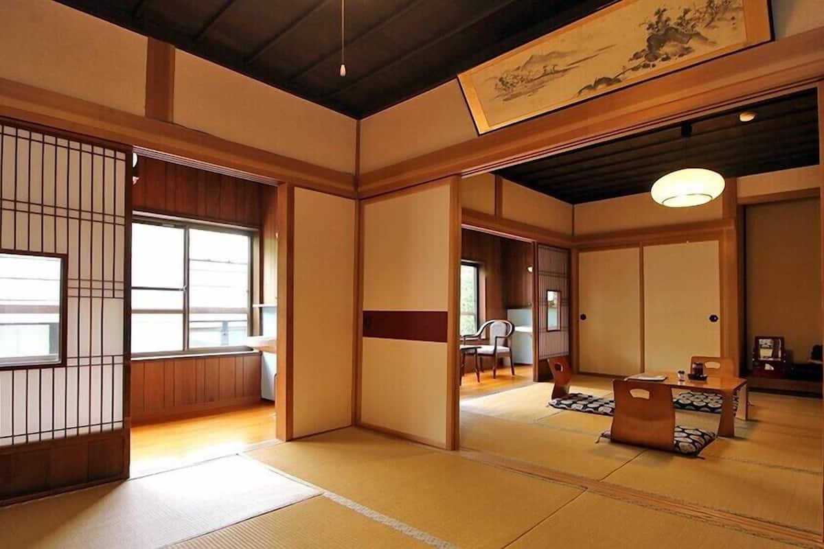 Una habitación japonesa tradicional con suelo de tatami, puertas correderas y una obra de arte colgante.