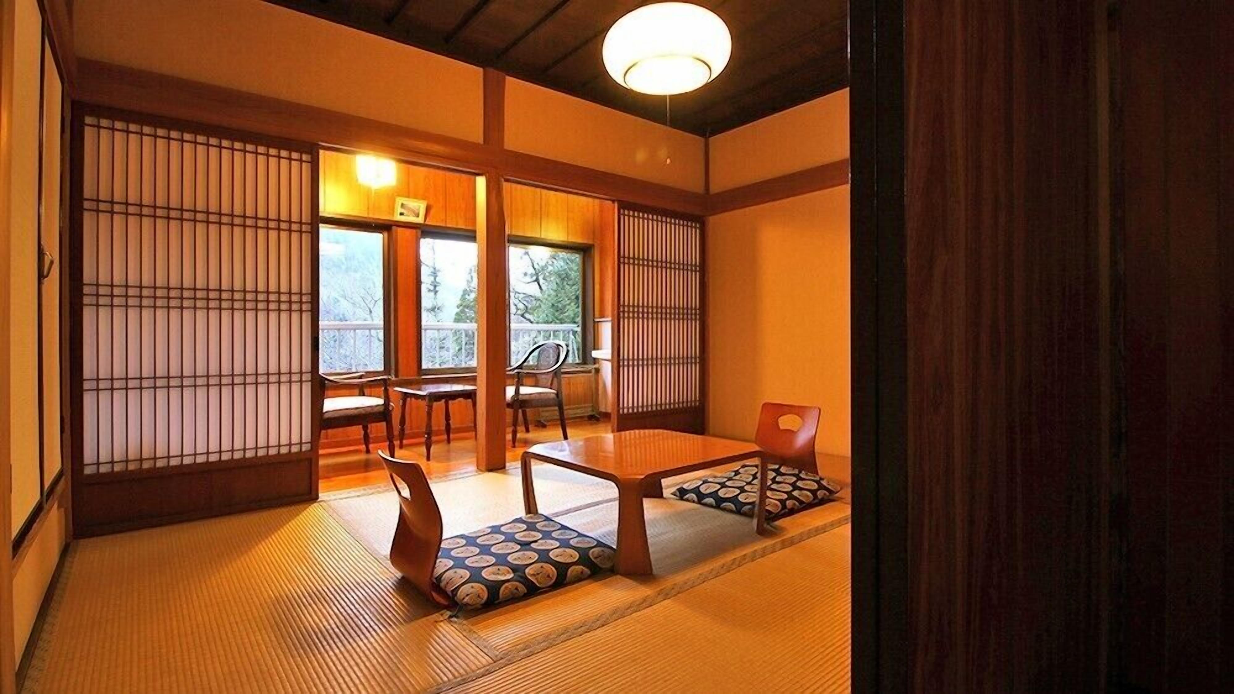 Una habitación japonesa tradicional con suelo de tatami, puertas correderas y una mesa baja con cojines.