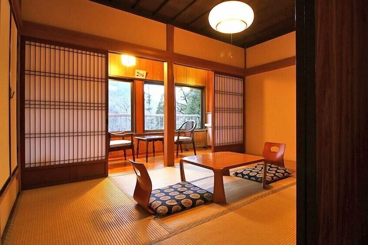 Una habitación japonesa tradicional con suelo de tatami, puertas correderas y una mesa baja con cojines.
