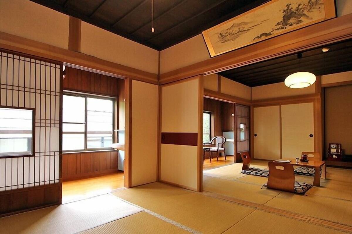 A traditional Japanese room with tatami flooring, sliding doors, and a hanging artwork.
