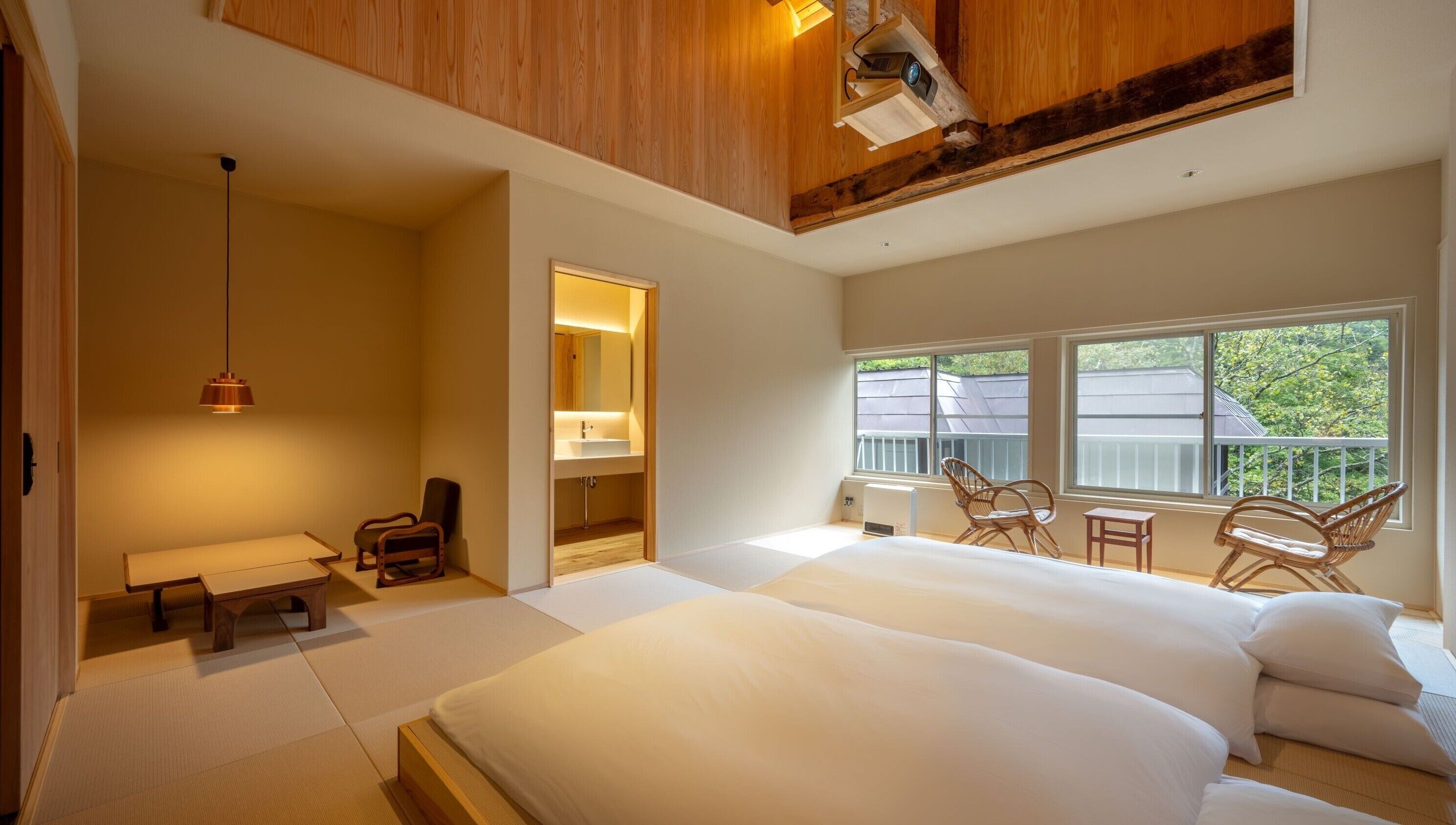 Un dormitorio con una cama grande, una zona de estar con sillas, una mesita y una ventana con vistas.