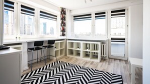 A modern kitchen with white cabinetry, black bar stools, and a black and white patterned rug. - Elegant Apartment Panoramic (Warsaw)