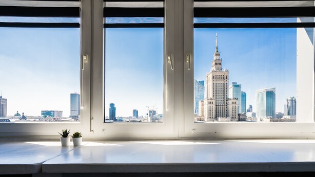 A view from a window with two chairs, a small plant, and a cityscape including a prominent building. - Elegant Apartment Panoramic (Warsaw)