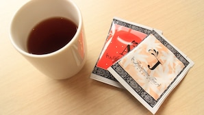 A white mug filled with a dark liquid, possibly tea or coffee, and a stack of cards with a floral design and the word 'Jasmine' on them.