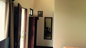 A bedroom with a wooden ceiling, a bed with an orange bedspread, a TV, and a mirror on the wall. - Cabinas Ledezma (Mogote de Bagaces)
