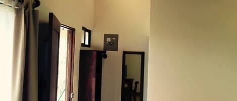 A bedroom with a wooden ceiling, a bed with an orange bedspread, a TV, and a mirror on the wall.