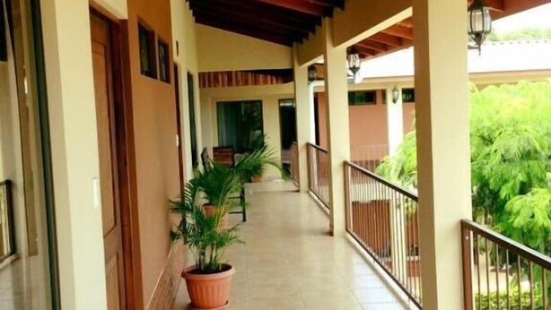 A covered corridor with potted plants, wooden benches, and a tiled floor. - Cabinas Ledezma (Mogote de Bagaces)