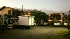 A residential area with a house, a utility truck, and a white pickup truck parked in front. - Cabinas Ledezma (Mogote de Bagaces)
