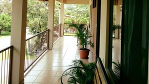 A covered corridor with wooden beams, potted plants, and a bench. - Cabinas Ledezma (Mogote de Bagaces)