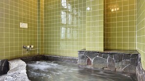 A spa area with tiled walls, a stone basin, and a water feature. - Shimizuya Ryokan (Nirasaki)