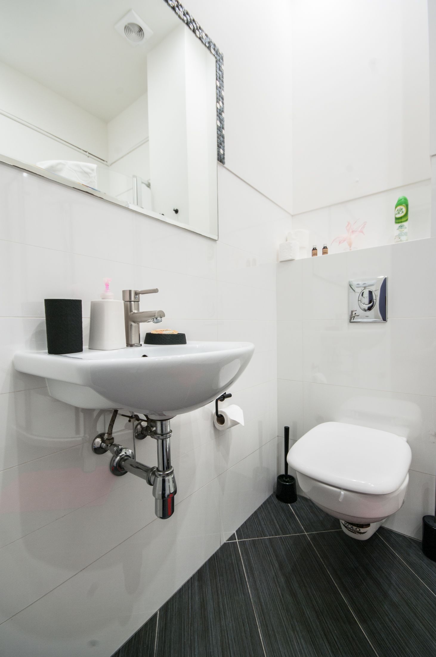 A modern bathroom with a white sink, mirror, and toilet.
