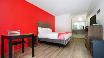 Una habitación de hotel con una cama, un escritorio y una silla.