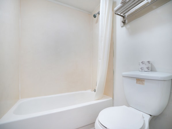 A bathroom with a bathtub, toilet, and a towel rack. - OYO Hotel Decatur I-285 The Perimeter (Decatur)