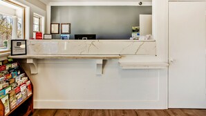 A reception desk with a marble top, framed pictures on the wall, and a wooden bookshelf with brochures. - OYO Hotel Ridgeland East (Ridgeland)