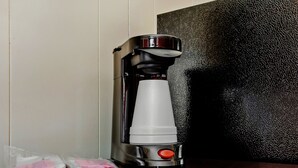 A coffee maker with a cup holder, a control button, and a small packet on the counter. - OYO Hotel Ridgeland East (Ridgeland)