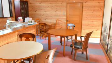 A cozy cabin interior with a dining area, wooden walls, a kitchen counter, and a door.