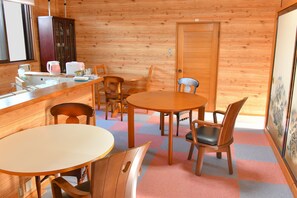 L’intérieur d’un chalet accueillant, avec un coin repas, des murs en bois, un comptoir de cuisine et une porte.