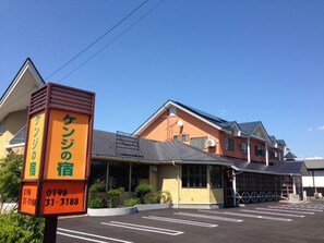 A hotel with a parking lot, a signboard with contact information, and a building with a sloped roof. - Shinkokyu (Senboku)