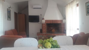 Cozy living room with a fireplace, television, and dining area for two.