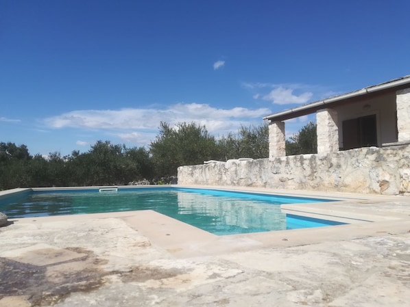 Relax by the serene pool surrounded by lush greenery and a stone wall.