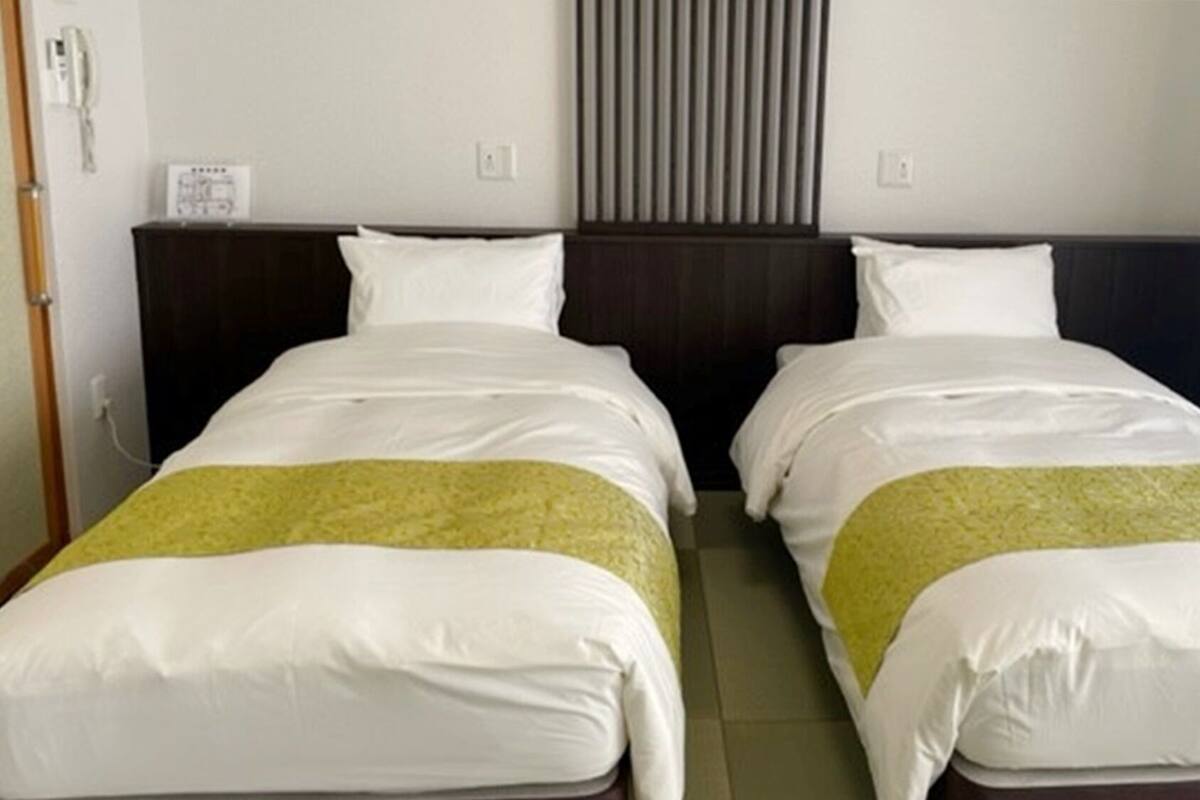 Une chambre d’hôtel avec deux lits, une fenêtre avec des rideaux et un climatiseur fixé au mur.