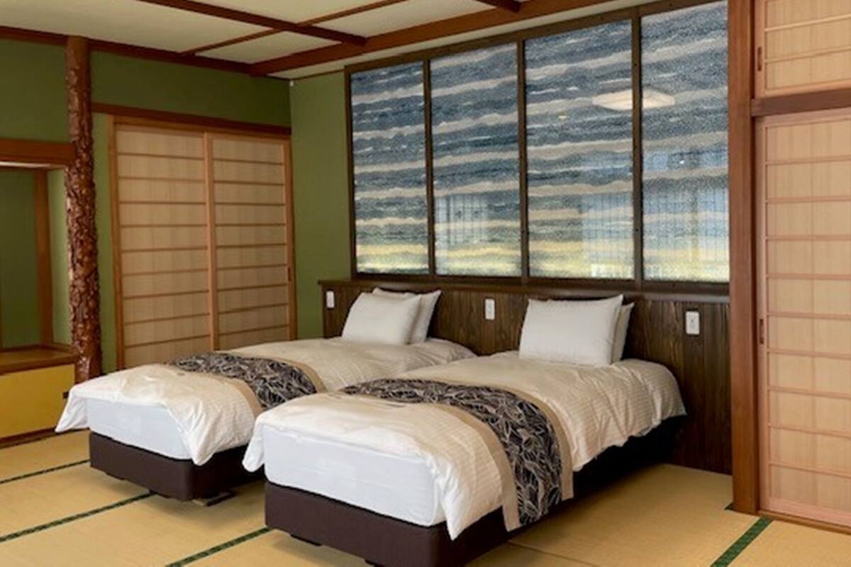 Une pièce de style japonais traditionnel, avec un sol recouvert de tatamis, un mur en panneaux coulissants de type shoji et une porte coulissante.