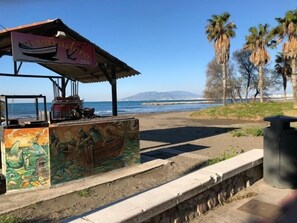 Ein Küstenkiosk mit Wandmalerei, überdachtem Sitzbereich und Blick auf das Meer.
