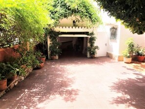 A courtyard with potted plants, a tiled floor, and a doorway leading to a building.