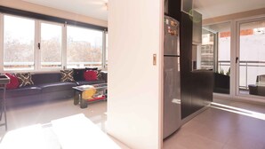 A modern kitchen with a built-in refrigerator, a dining area with a table and chairs, and large windows offering a view of the city.