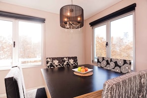 Enjoy meals in this dining area with a table for two, a chandelier, and a view of the surrounding trees.