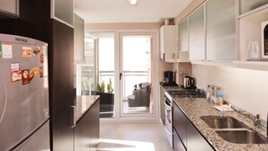 A modern kitchen with stainless steel appliances, a granite countertop, and a sliding glass door leading to a balcony.