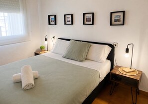 Un lit bien fait, avec une serviette roulée, une lampe de chevet et une petite plante posée sur une table de chevet.