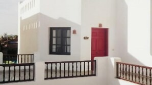 Un edificio blanco con una puerta roja y una ventana.