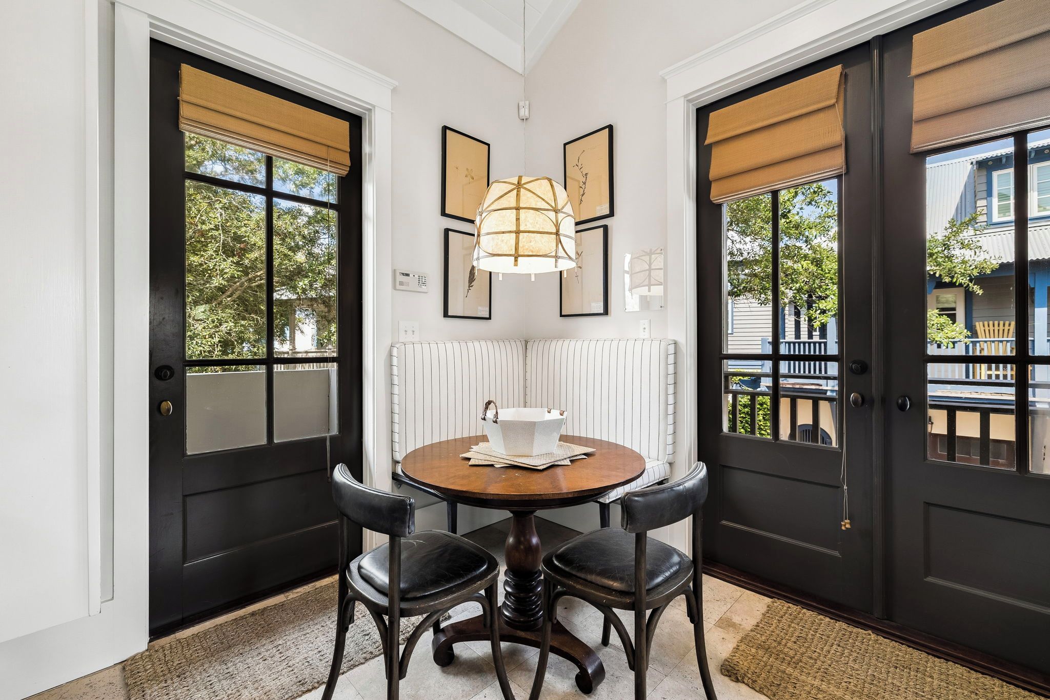 A corner room with a round table, two chairs, a radiator, and a window with a view of the outside.