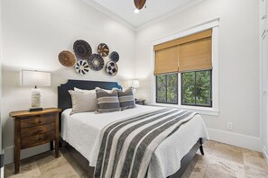Une chambre à coucher comprenant un lit, des tables de chevet, une fenêtre avec des stores et des éléments de décoration murale.