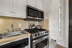 A kitchen with a stainless steel stove, oven, and microwave, a sink with a faucet, and a cabinet above the stove. - Carriage House | 30 Sec Walk to Beach | Pool Access | Across Eastern Green (Rosemary Beach)
