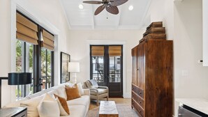 Un salon spacieux avec un canapé blanc, un meuble en bois et un ventilateur de plafond.