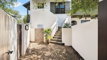 A modern house with a curved staircase leading to a second floor, surrounded by white walls and a wooden fence.