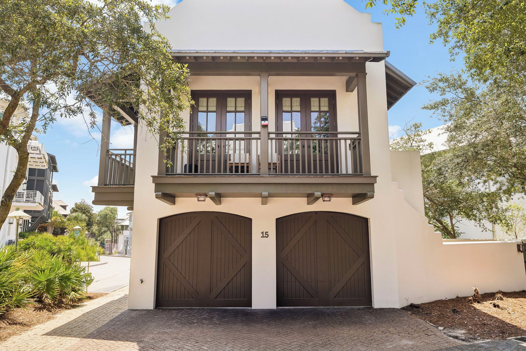 A two-story building with a balcony, large garage doors, and a number '15' on the wall.