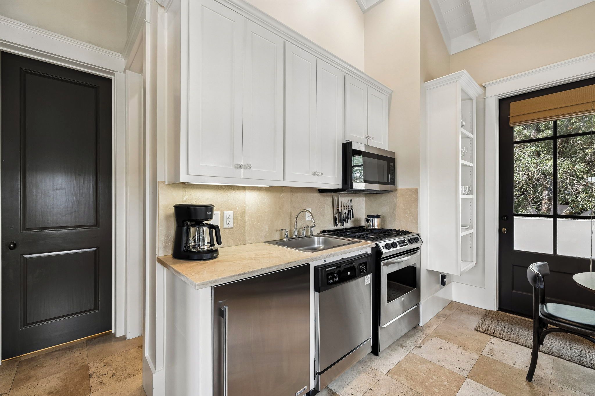 A modern kitchen with white cabinetry, a stainless steel dishwasher, a gas stove, and a microwave.