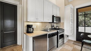 A modern kitchen with white cabinetry, a stainless steel dishwasher, a gas stove, and a microwave. - Carriage House | 30 Sec Walk to Beach | Pool Access | Across Eastern Green (Rosemary Beach)