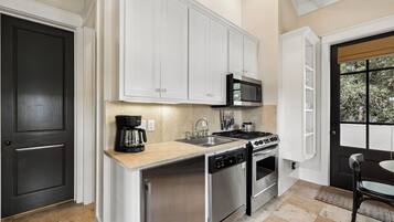A modern kitchen with white cabinetry, a stainless steel dishwasher, a gas stove, and a microwave.