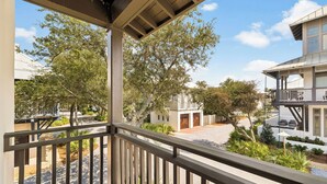 A balcony with a view of a residential area, including a house with a garage and a tree-lined street. - Carriage House | 30 Sec Walk to Beach | Pool Access | Across Eastern Green (Rosemary Beach)