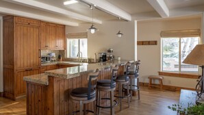 Una cocina con armarios de madera, encimera de granito y barra con taburetes.