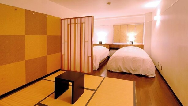 A room with two beds, a small table, and a sliding door. - Okayama Green Hotel (Okayama)