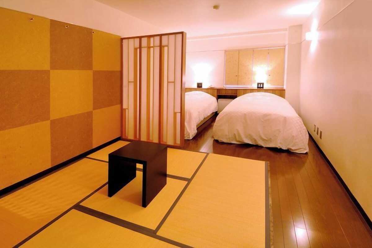 A room with two beds, a small table, and a sliding door.