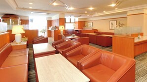 A hotel lobby with leather seating, a reception desk, and a dining area. - Okayama Green Hotel (Okayama)