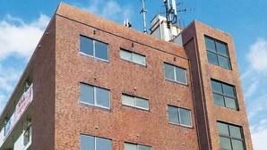 Un immeuble de plusieurs étages, construit en briques, avec de nombreuses fenêtres et une antenne visible sur le toit.