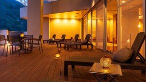 A modern outdoor lounge area with seating and tables, a wooden deck, and a glass wall overlooking a mountainous landscape. - Kinu No Keikoku Hekiryu (Nikko)