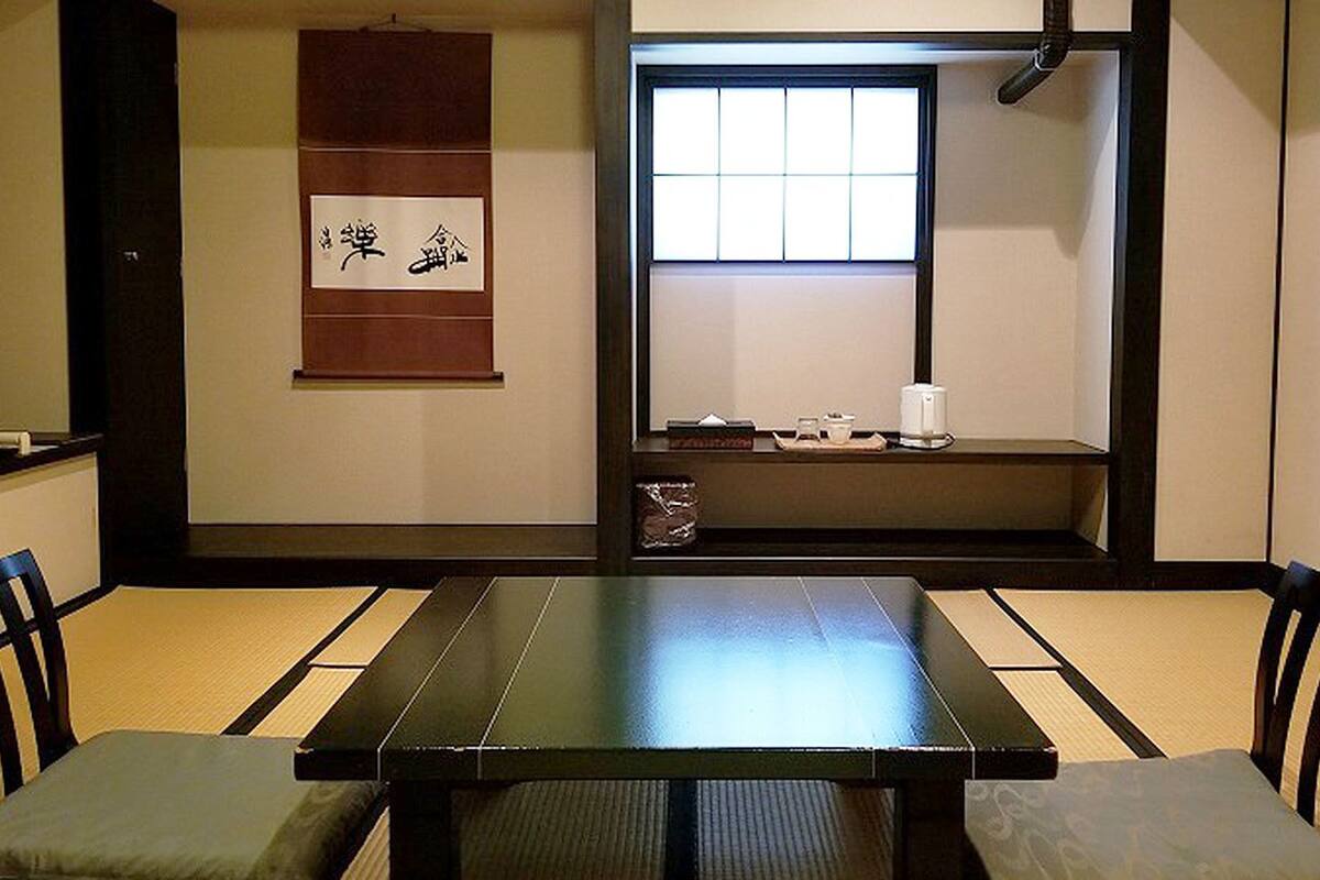 Een traditionele Japanse kamer met tatami vloerbedekking, een lage tafel en schuifdeuren.